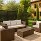 Outdoor patio furniture set with cushions on a patio in front of a house.